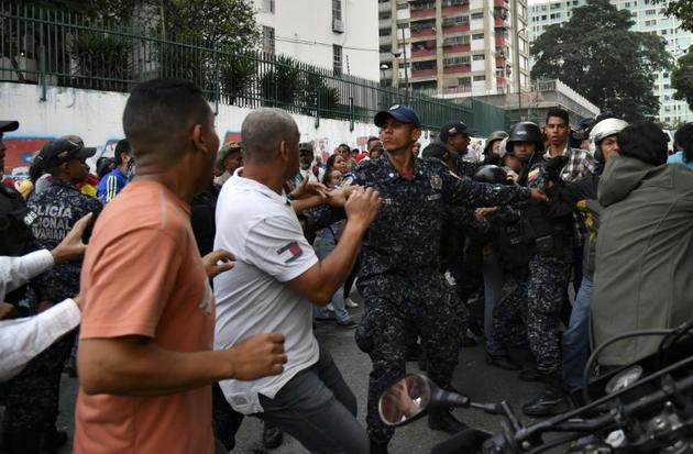 Des policiers vénézuéliens tentent d'éviter une confrontation entre partisans du président Nicolas Maduro et de l'opposant Juan Guaido, le 29 mars 2019 à Caracas [YURI CORTEZ / AFP]