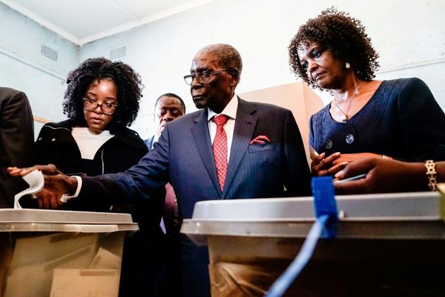 L'ancien président zimbabwéen Robert Mugabe entouré de sa fille Bona (G) et de sa femme Grace (D) vote dans une école à Harare, le 30 juillet 2018 [Zinyange AUNTONY / AFP]