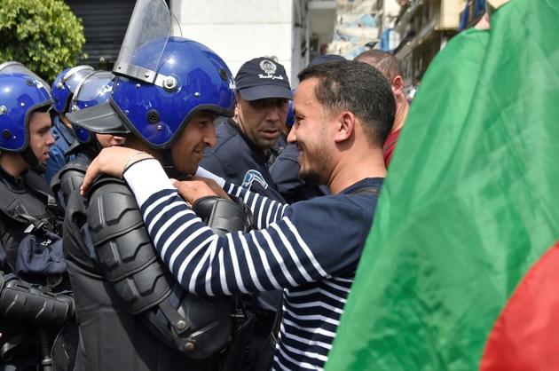 Un Algérien embrasse un agent des forces de l'ordre lors d'une manifestation anti-gouvernementale le 23 avril 2019 à Alger [RYAD KRAMDI                         / AFP/Archives]