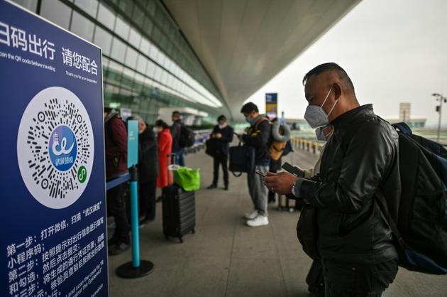 Des voyageurs attendent de passer les contrôles à leur arrivée à l'aéroport de Wuhan, le 11 avril 2020 dans la province chinoise du Hubei [Hector RETAMAL / AFP]