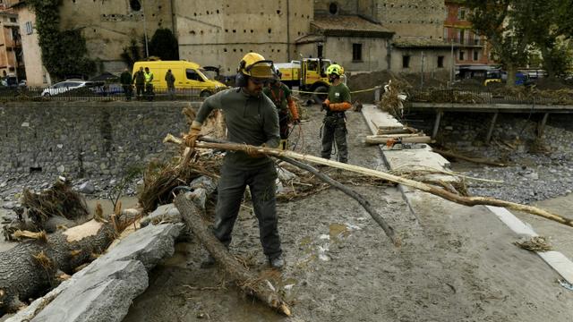 Des équipes de secours enlèvent des arbres tombés sur un pont à Breil-sur-Roya (sud-est de la France), le 4 octobre 2020 [NICOLAS TUCAT / AFP]