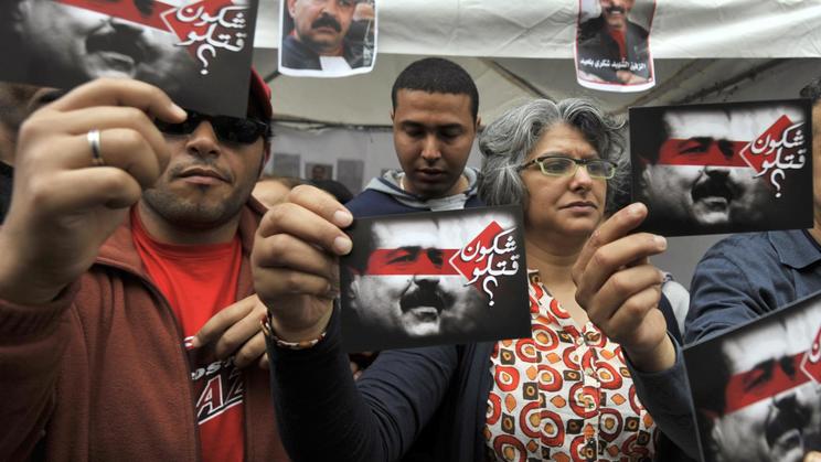 Des proches de l'opposant tunisien assassiné Chokri Belaïd brandissent sa photo à Tunis, le 1er mai 2013 [Fethi Belaïd / AFP/Archives]