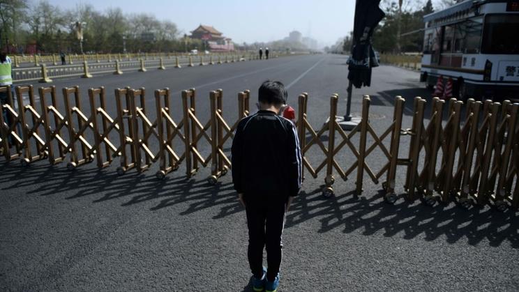 Un jeune garçon rend hommage aux morts du coronavirus lors d'une moment de recueillement national, à Pékin place Tiananmen, le 4 avril 2020 [GREG BAKER / AFP]