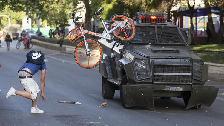 Un manifestant balance un vélo contre un véhicule de l'armée, le 18 octobre à Santiago.