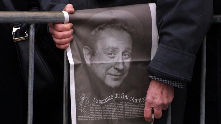 Un homme tient une photographie de Charles Trenet, le 23 février 2001 devant l'église de la Madeleine à Paris [Joel Saget / AFP/Archives]