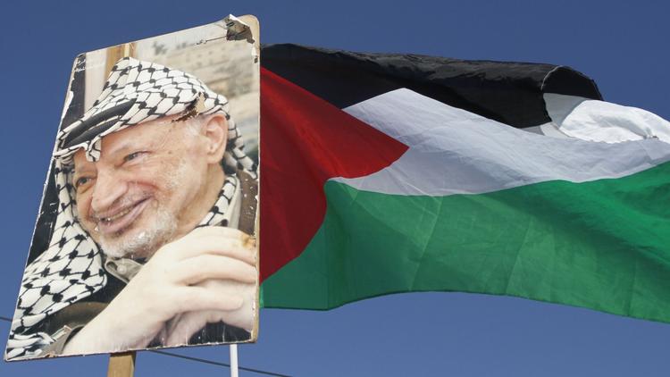 Le portrait de Yasser Arafat près du drapeau palestinien, le 11 novembre 2011 près de Bethléem [Musa al Shaer / AFP/Archives]