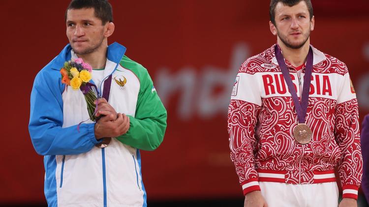 Les lutteurs ouzbek Soslan Tigiev (G) et russe Denis Tsargush (D) sur le podium des JO-2012 lors de la remise de leur médaille de bronze dans la catégorie des - de 74 kg, le 10 août 2012 à Londres [ / AFP]