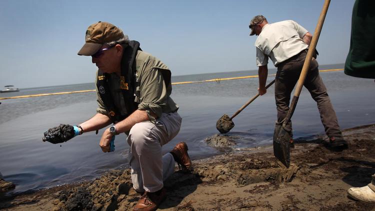 Des personnes retirent du pétrole d'une plage de Louisiane, le 19 avril 2011, un an après la marée noire dans le Golfe du Mexique [John Moore / AFP/Getty Images/Archives]