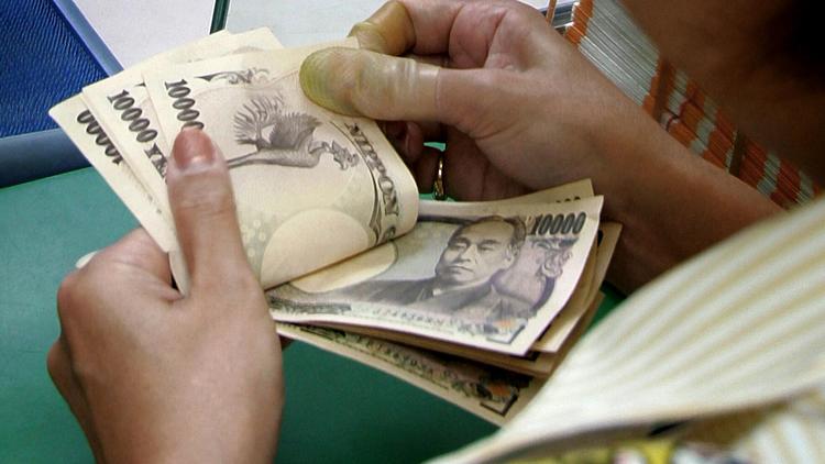 Une femme compte des billets de banque à Tokyo [Kazuhiro Nogi / AFP/Archives]