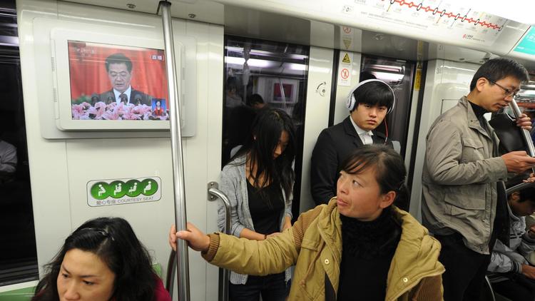 Des personnes dans le métro de Shanghai suivent sur un écran le discours du président chinois Hu Jintao à l'ouverture à Pékin du 18e congrès du PCC, le 8 novembre 2012 [Peter Parks / AFP]