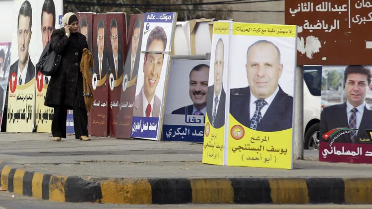 Une femme passe devant des affiches électorales, le 29 décembre 2012 à Amman, en vue des législatives de janvier [Khalil Mazraawi / AFP]