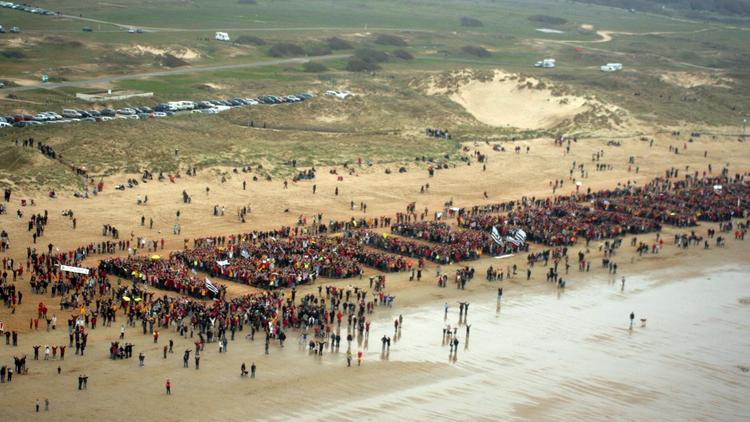 Vue aérienne prise le 25 mars 2007, montrant des personnes formant le nom du collectif "Le peuple des dunes" sur une plage d'Erdeven, lors d'une manifestation contre un projet d'extraction de sable au large de la presqu'île de Quiberon, au sud de la Bretagne [Gérard Guilias / AFP/Archives]
