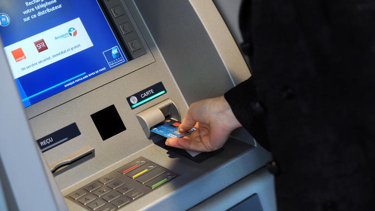 Une personne retire de l'argent dans un distributeur automatique [Bertrand Guay / AFP/Archives]