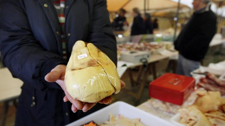 Un homme présente un foie gras sur un marché [Patrick Bernard / AFP/Archives]
