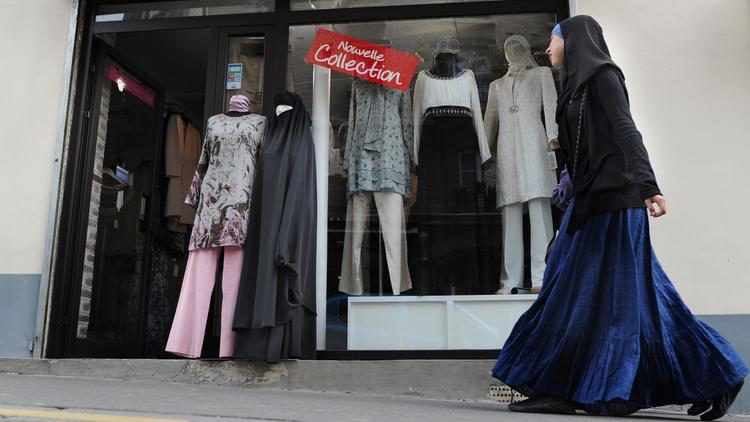 Une femme voilée passe devant une boutique vendant des tenues islamiques, à Paris, en avril 2011 [Miguel Medina / AFP/Archives]