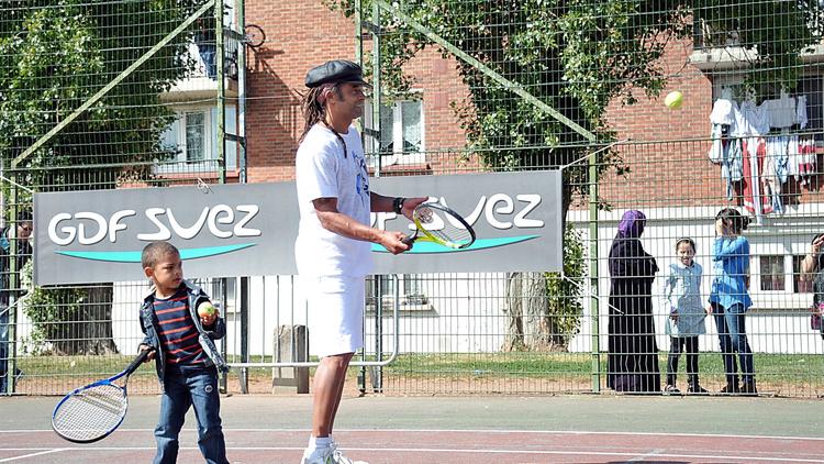 Le chanteur et ancien champion de tennis, Yannick Noah (D) joue au tennis avec un enfant, membre de son association "Fête le mur", le 20 Mai 2011 à Lille [Philippe Huguen / AFP/Archives]