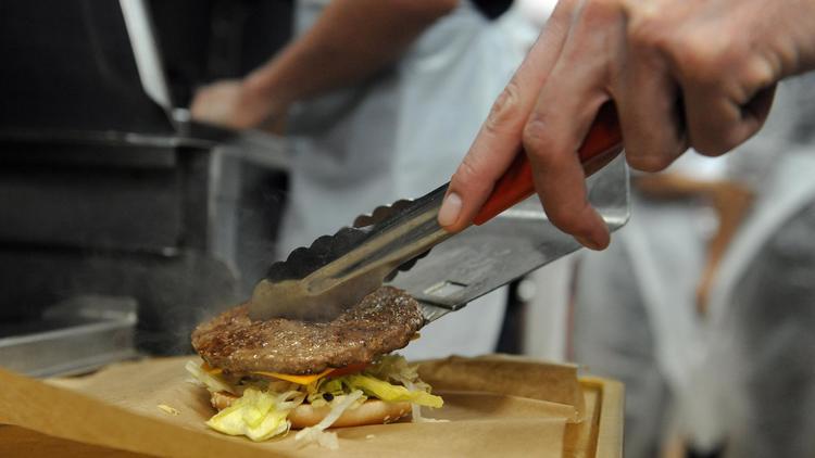 Un homme en cuisine prépare un hamburger dans une chaîne de restauration rapide [Remy Gabalda / AFP/Archives]