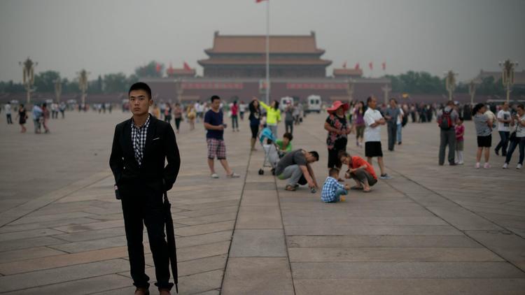 Un policier en civil (G) suit des journalistes sur la place Tiananmen à Pékin le 4 juin 2013 [Ed Jones / AFP]
