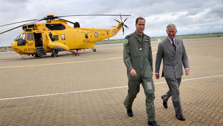 Le prince William avec son père le prince Charles le 9 juillet 2012. Derrière l’hélicoptère Sea King RAF avec lequel le prince à sauver les deux adolescentes. 