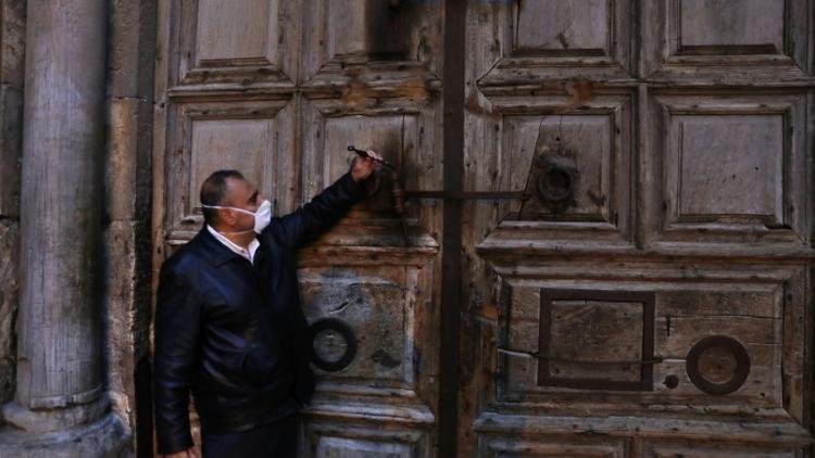 Adeeb Joudeh, gardien de la clé qui permet d'ouvrir et fermer la basilique du Saint-Sépulcre à Jérusalem, ferme le 25 mars 2020 l'église dans le cadre de mesures décrétées face à la propogation du nouveau coronavirus  [Ahmad GHARABLI / AFP]