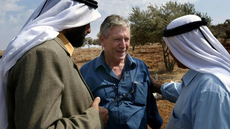 L'écrivain israélien Amos Oz discute avec des Palestiniens après la récolte d'olives à Aqraba, en Cisjordanie, le 30 octobre 2002. [Menahem KAHANA / AFP/Archives]