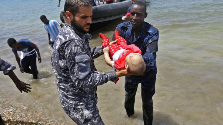 Le corps d'un des trois bénés repêchés vendredi après le naufrage d'une embarcation est porté par des membres des forces de sécurité libyennes, le 29 juin 2018 à al-Hmidiya [Mahmud TURKIA / AFP]