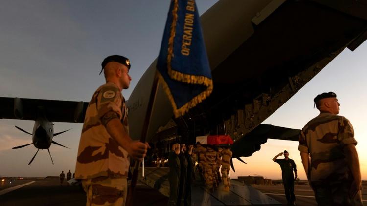 Les cercueils recouverts du drapeau aux couleurs de la France, près d'un soldat brandissant un étendard portant la mention "Opération Barkhane", avant d'être embarqués dans le gros porteur. Photo prise le 30 novembre 2019 et fournie le 1er... [THOMAS PAUDELEUX / ECPAD/AFP]