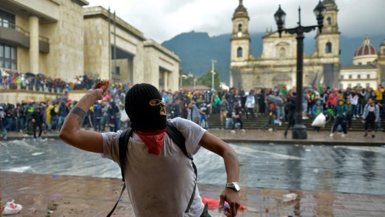 Un manifestant lançant une pierre contre la police, le 21 novembre 2019 à Bogota. [RAUL ARBOLEDA / AFP]