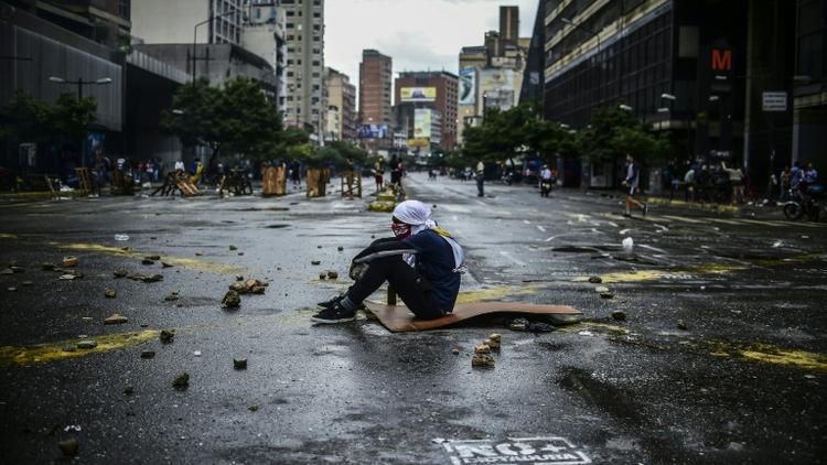 Un opposant à Nicolas Maduro assis dans la rue pendant un blocage le 19 juillet 2017 à Caracas. [RONALDO SCHEMIDT / AFP]