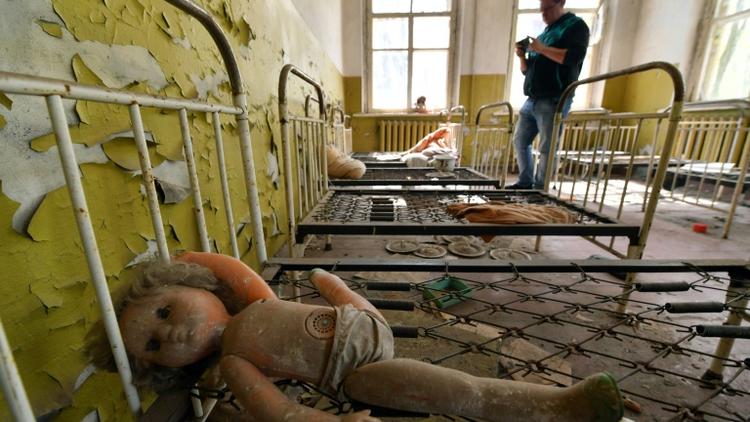 Un touriste prend des photos dans une école maternelle abandonnée dans le village de Kopachi près de la centrale de Tchernobyl le 23 avril 2018 [Sergei SUPINSKY / AFP]