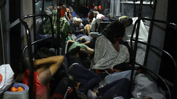 Des migrants dorment dans des bus hongrois qui les emmènent jusqu'à la frontière austro-hongroise samedi 5 septembre 2015 [PETER KOHALMI / AFP]