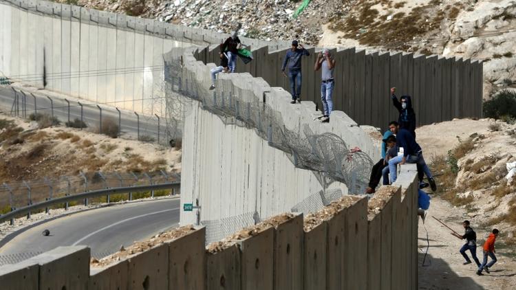 Des Palestiniens debout sur le mur séparant la ville d'Abu Dis en Cisjordanie et Jérusalem est le 28 octobre 2015 [Ahmad Gharabli / AFP/Archives]
