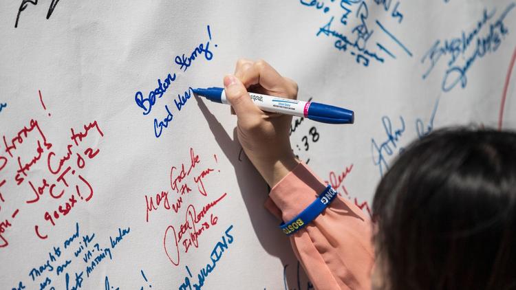 Une femme rédige un hommage en souvenir des victimes des attentats de Boston, le 14 avril 2014 à Boston [Andrew Burton / Getty Images/AFP]