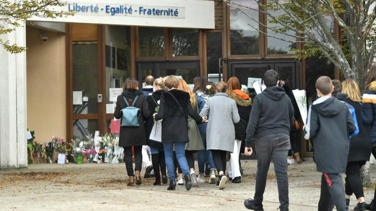 Adultes et enfants viennent déposer des fleurs devant l'école de Conflans-Sainte-Honorine, le 17 octobre 2020 au lendemain de la décapitation d'un des professeurs [Bertrand GUAY / AFP]
