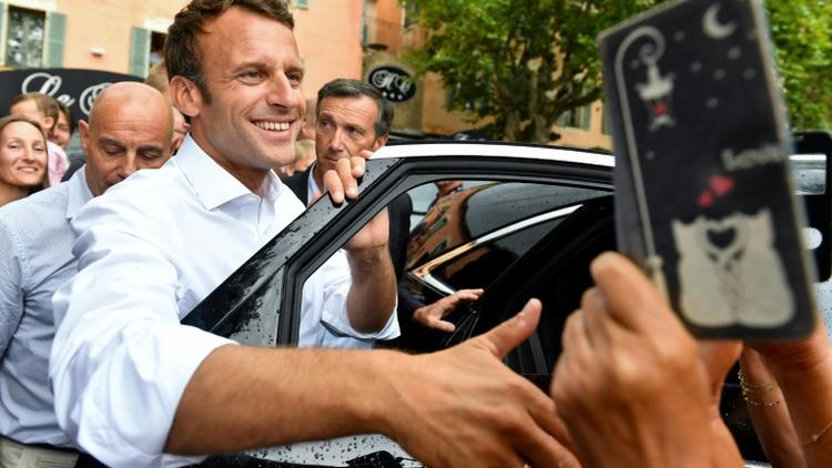 Le président Emmanuel Macron salue la foule après s'être entretenu avec le maire de la commune de Bormes-les-Mimosas (Var), le 27 juillet 2019  [GERARD JULIEN / AFP]
