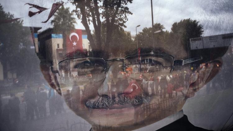 Photo prise à travers une banderole électorale tranparente affichant un portrait du Premier ministre turc Ahmet Davutoglu le 29 octobre 2015 à Istanbul [DIMITAR DILKOFF / AFP]