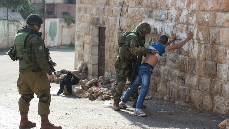 Des soldats israéliens fouillent un Palestinien, le 29 octobre 2015 à Hébron, en Cisjordanie [MENAHEM KAHANA / AFP]