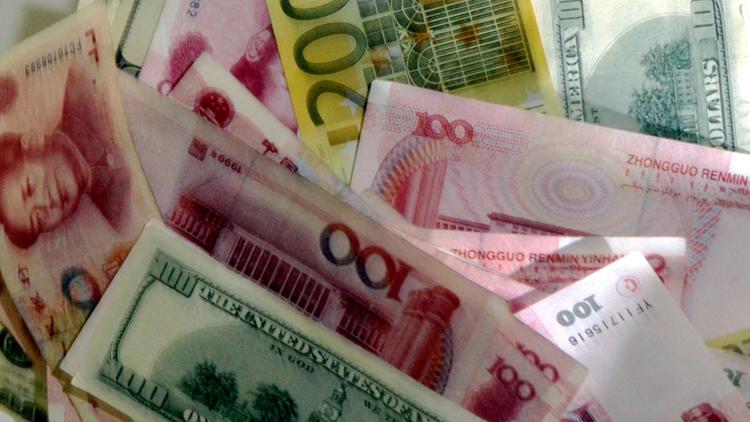 Des billets de dollars, de yuans et d'euros [Peter Parks / AFP/Archives]