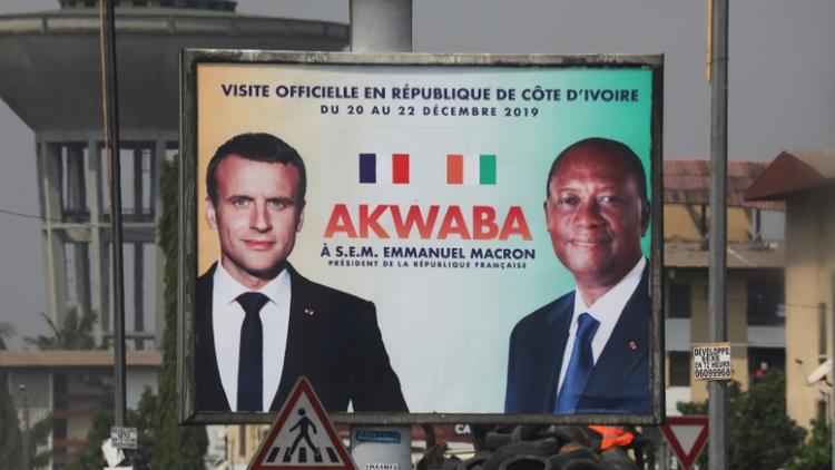 Une affiche montrant Emmanuel Macron (g) et son homologue ivoirien Alassane Ouattara à Abidjan le 19 décembre 2019 [Ludovic MARIN / AFP]