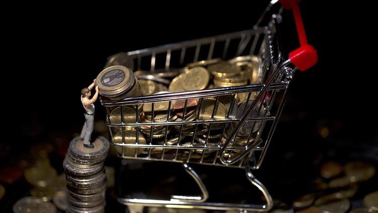Une figurine remplit un  caddy miniature de pièces de monnaie [Joel Saget / AFP/Archives]
