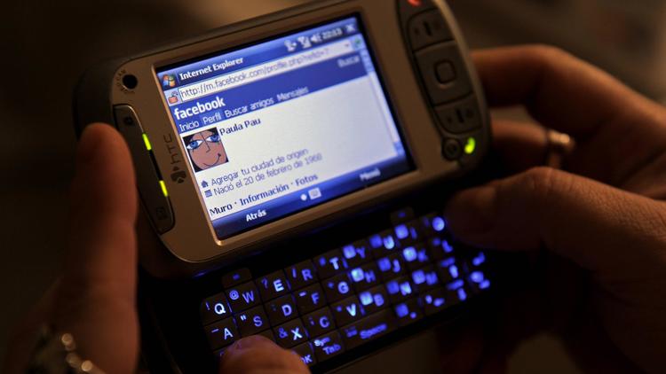 Une femme se connecte sur une page internet avec son téléphone portable [Juan Mabromata / AFP/Archives]