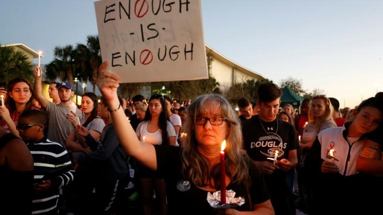 Une manifestante brandit une pancarte clamant "Assez c'est assez !" lors d'une veillée pour les victimes de la fusillade du lycée à Parkland qui a coûté la vie à 17 personnes  [RHONA WISE / AFP]