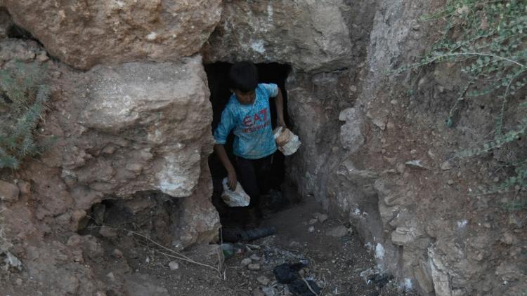 Un enfant transporte des pierres durant des travaux de construction d'un abri souterrain, dans la province syrienne d'Idleb, le 15 septembre 2018 [OMAR HAJ KADOUR / AFP]