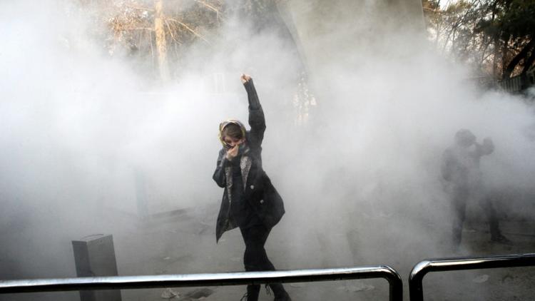 Une Iranienne lève le poing au milieu de gaz lacrymogènes devant l'université de Téhéran lors d'une manifestation contre le pouvoir le 30 décembre 2017 [STR / AFP]