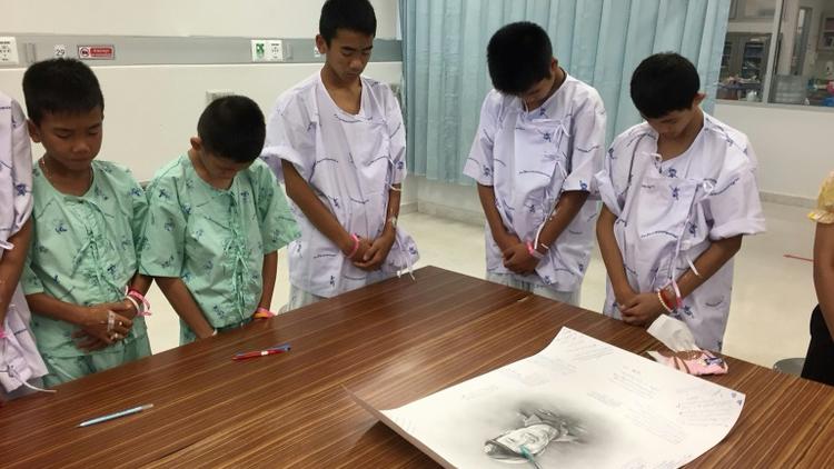 Photo prise le 14 juillet et diffusée le 15 juillet par le ministère de la Santé montre des jeunes footballeurs rescapés d'une grotte en Thaïlande avec un portrait du plongeur mort à l'hôpital de Chiang Rai Prachanukroh [Handout / Chiang Rai Prachanukroh Hospital/AFP]