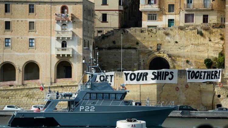 Un bateau des gardes-côtes maltais patrouillent dans la baie de Birgu à Malte, devant des banderoles où l'on peut lire "Get your ships together", le 23 septembre 2019 [Matthew Mirabelli / AFP]