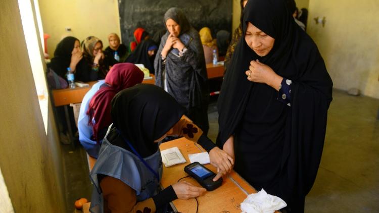 Une employée électorale enregistre l'empreinte biométique d'une votante lors des législatives, le 20 octobre 2018 à Hérat, en Afghanistan [HOSHANG HASHIMI / AFP]