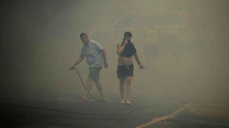 Des habitants se protègent des fumées lors d'un incendie de forêt à Mazagon, près d'un parc naturel dans le sud-ouest de l'Espagne, le 25 juin 2017  [CRISTINA QUICLER                     / AFP]