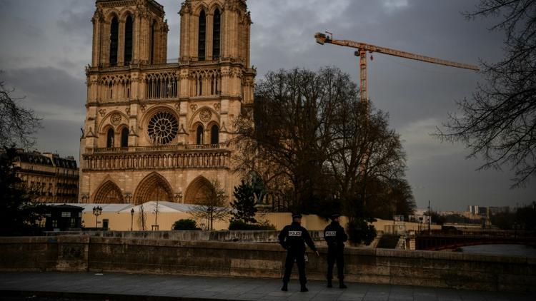 Des policiers patrouillent aux abords désertés de la cathédrale Notre-Dame de Paris, habituellement peuplés de touristes, le 17 mars 2020 [Christophe ARCHAMBAULT / AFP]