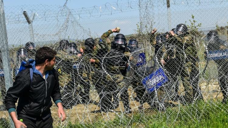 Des policiers madéconiens lancent des pierres sur les migrants le 10 avril 2016 à Idomeni [BULENT KILIC / AFP]